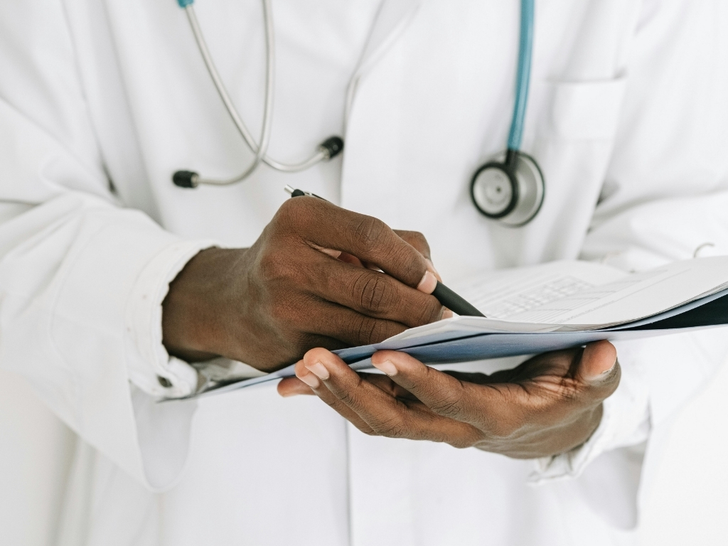 Doctor reading paper records with pen